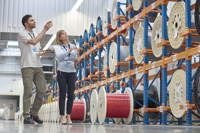Руководители мужского и женского пола проверяют инвентаризацию на заводе волоконной оптики — стоковое фото
