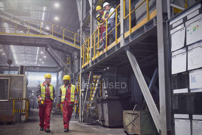 Adult steelworkers walking in steel mill together — Stock Photo