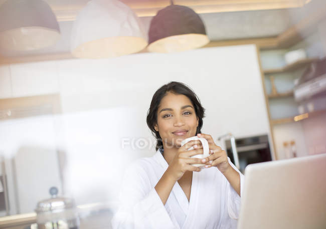 Retrato mulher confiante em roupão de banho beber café no laptop — Fotografia de Stock