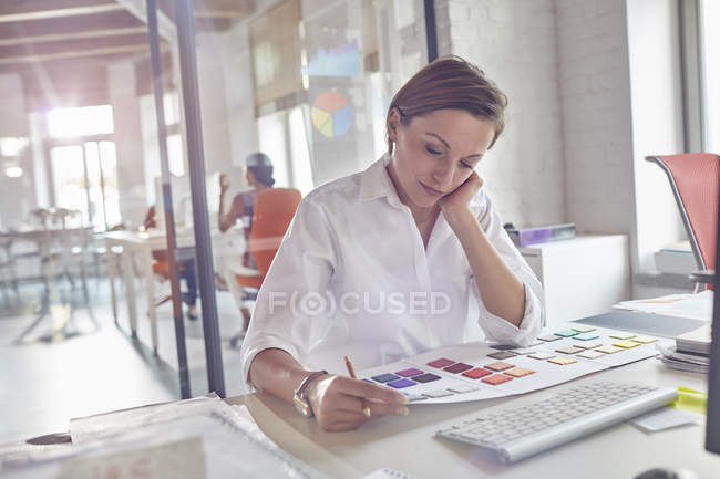 Female design professional reviewing color swatches at modern office — Stock Photo