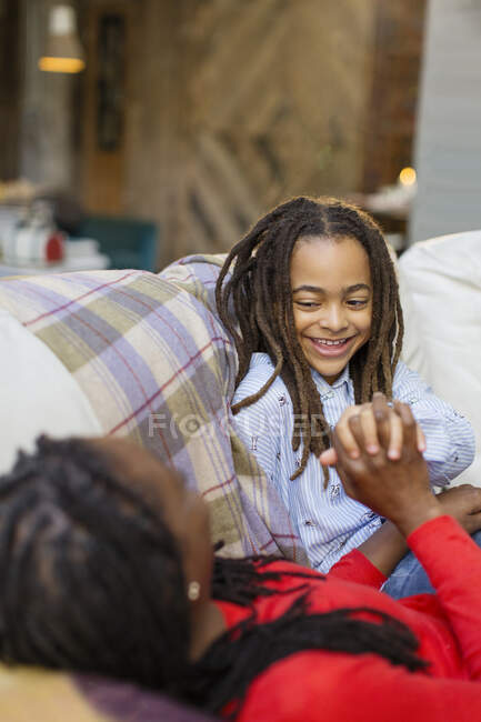 Affectionate mother and daughter holding hands on sofa — Stock Photo