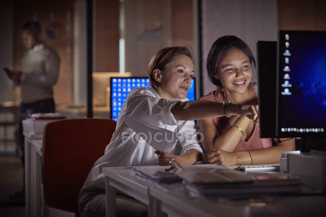 Женщины-бизнесмены, работающие допоздна за компьютером в темном офисе ночью — стоковое фото