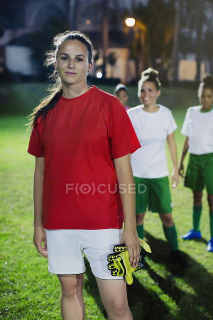 Portrait confident young female soccer player on field at night — Stock Photo