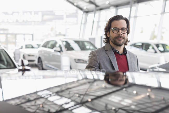 Portrait smiling, confident car salesman in car dealership showroom — Stock Photo