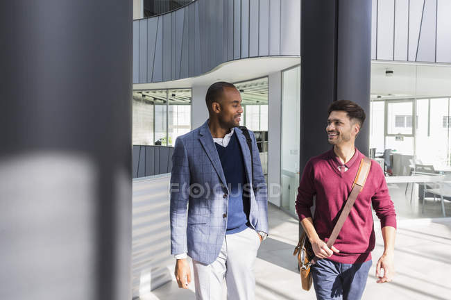 Бизнесмены разговаривают и ходят в современном офисном холле — стоковое фото