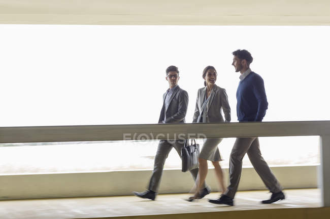 Uomini d'affari che camminano e parlano lungo la passerella — Foto stock