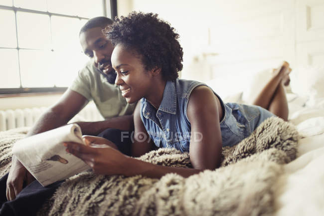 Пара розслабляється, читає газету на ліжку — стокове фото