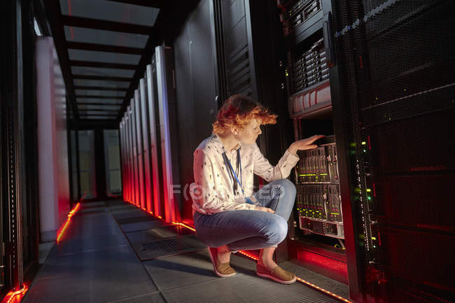 Жіночий IT-технік, що вивчає панель в темній кімнаті сервера — стокове фото