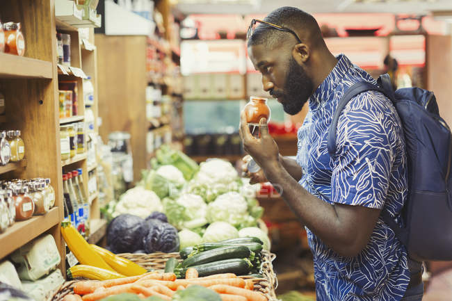 Mann kauft ein, riecht Gewürze im Supermarkt — Stockfoto