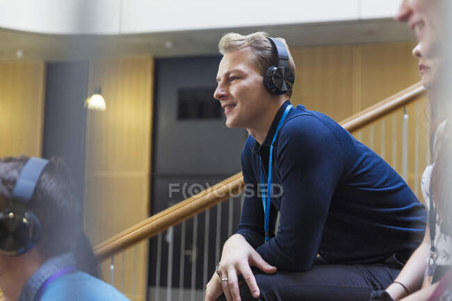 Lächelnder, aufmerksamer Mann hört Kopfhörer im Konferenzpublikum — Stockfoto
