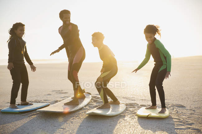 Сімейні серфери практикують на дошках для серфінгу на сонячному літньому пляжі — стокове фото