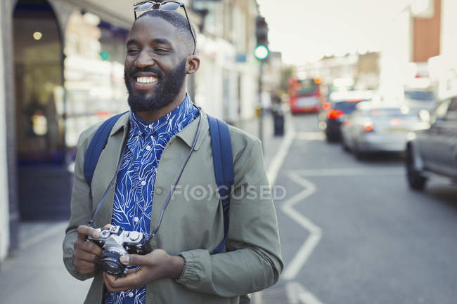 Lächelnder junger männlicher Tourist mit Kamera auf urbaner Straße — Stockfoto