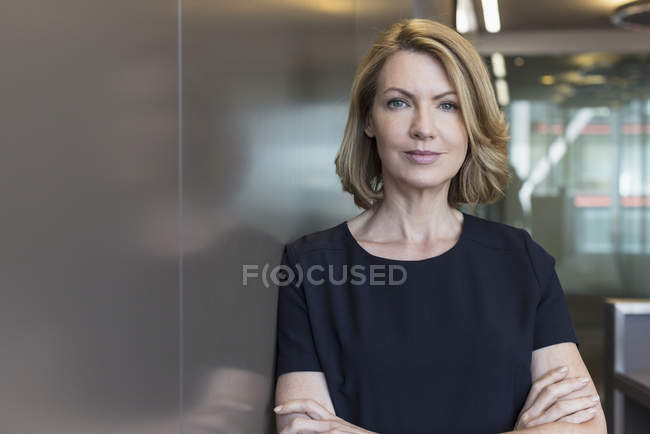 Retrato mujer de negocios senior con los brazos cruzados en la oficina moderna - foto de stock