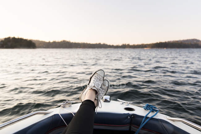Perspectiva personal mujer paseos en bote con los pies en el lago tranquilo - foto de stock