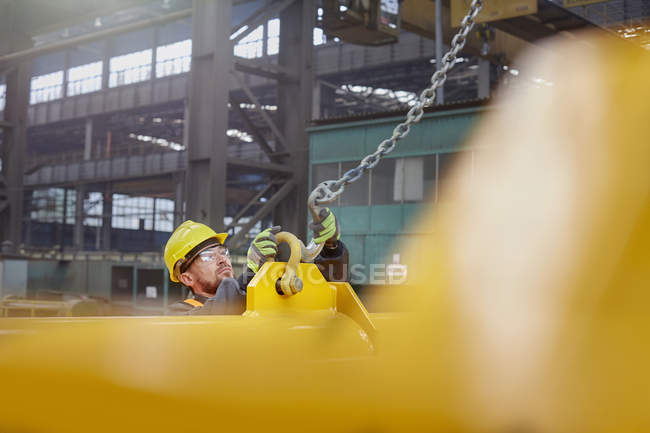 Чоловічий заводський працівник прикріплює ланцюг до обладнання — стокове фото