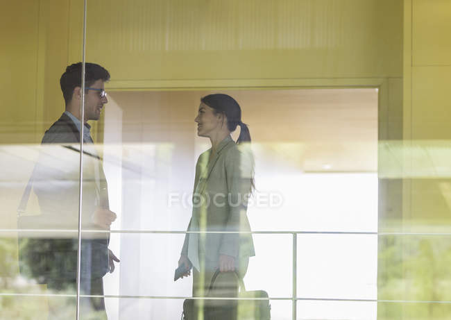 Empresário e empresária conversando no corredor de escritórios moderno — Fotografia de Stock