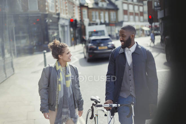 Пара гуляє, спілкується з велосипедом на міській вулиці — стокове фото