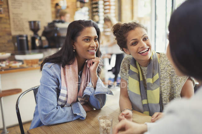 Lächelnde Freundinnen unterhalten sich am Café-Tisch — Stockfoto