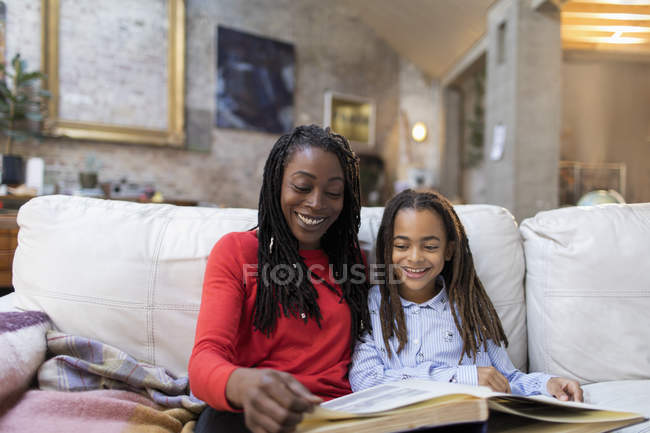 Mother and daughter looking at photo album on sofa — Stock Photo