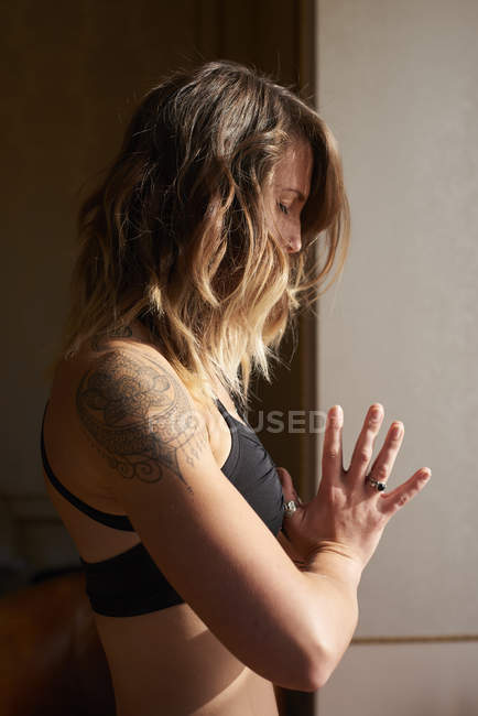 Ruhige Frau mit Tätowierung meditiert mit den Händen im Herzzentrum, anjali mudra — Stockfoto