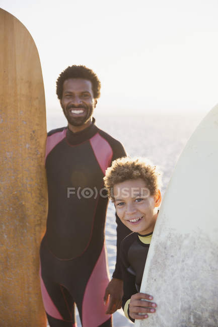Портрет усміхненого батька і сина з дошками для серфінгу на сонячному літньому пляжі — стокове фото