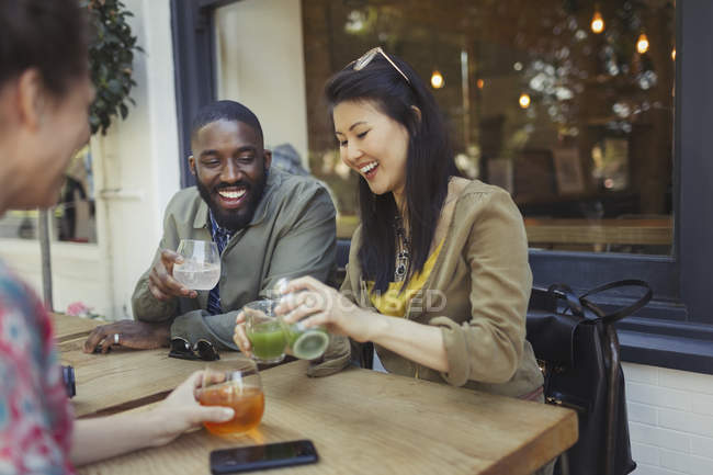 Sorridente giovani amici bere succo di frutta al caffè marciapiede — Foto stock