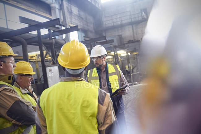 Supervisor y trabajadores siderúrgicos conversando en reunión en fábrica de acero - foto de stock