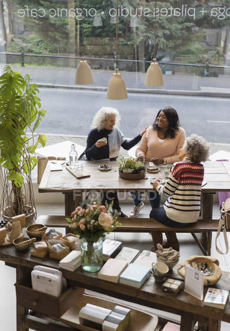 Жінки розмовляють друзями, п'ють чай в магазині — стокове фото