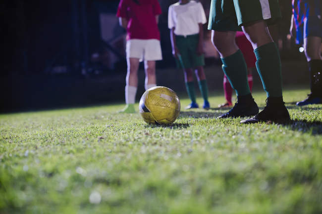Cropped image of young female soccer players practicing on field at night — Stock Photo