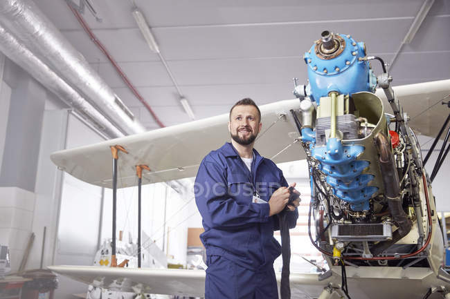 Portrait confident male airplane mechanic working on biplane in hangar — Stock Photo
