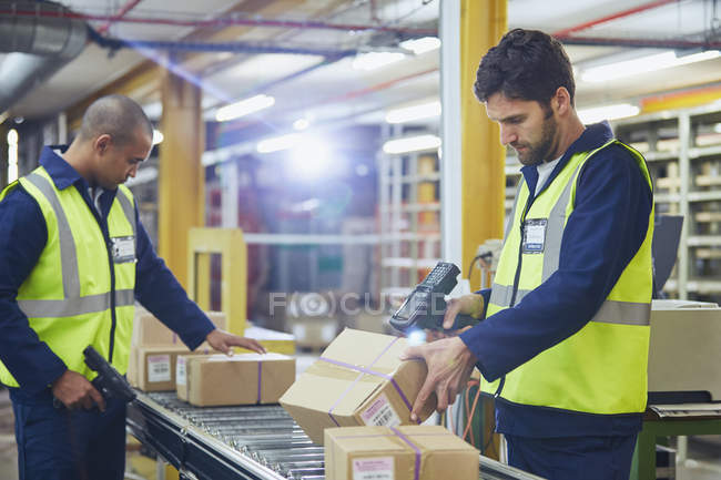 Trabalhadores de digitalização e processamento de caixas na correia transportadora em armazém de distribuição — Fotografia de Stock