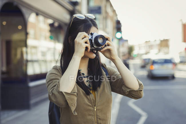 Молода жінка-туристка фотографується з камерою на міській вулиці — стокове фото