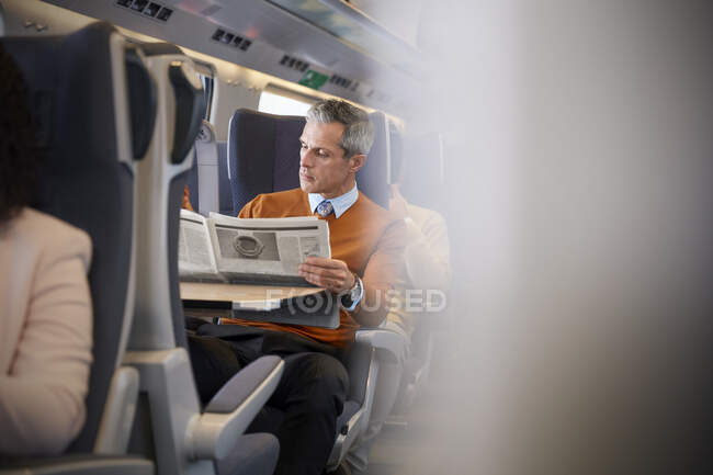 Empresário lendo jornal no trem de passageiros — Fotografia de Stock
