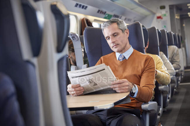 Homme d'affaires lisant un journal dans un train de voyageurs — Photo de stock