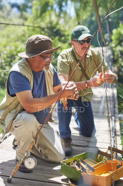 Active senior male friends preparing fishing lines — Stock Photo