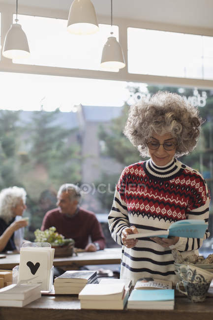 Donna anziana che legge libro in negozio — Foto stock