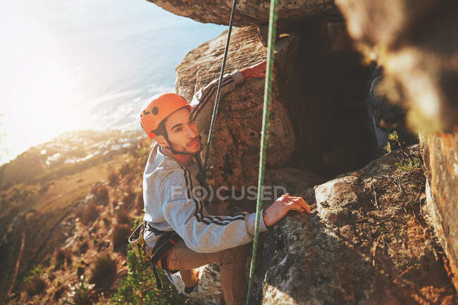 Escalador masculino enfocado escalando rocas - foto de stock