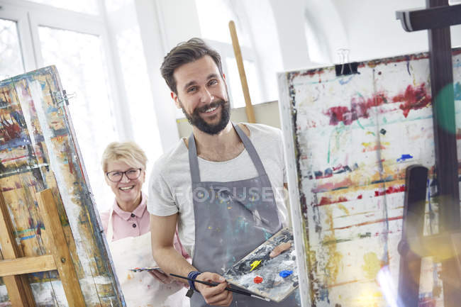 Portrait smiling artists painting at easels in art class studio — Stock Photo
