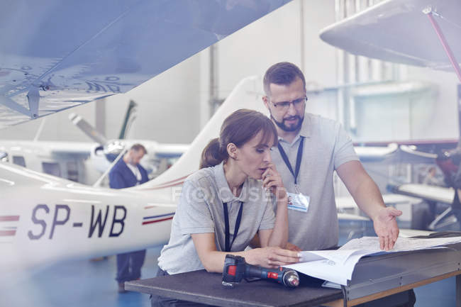 Airplane mechanics reviewing plans in hangar — Stock Photo