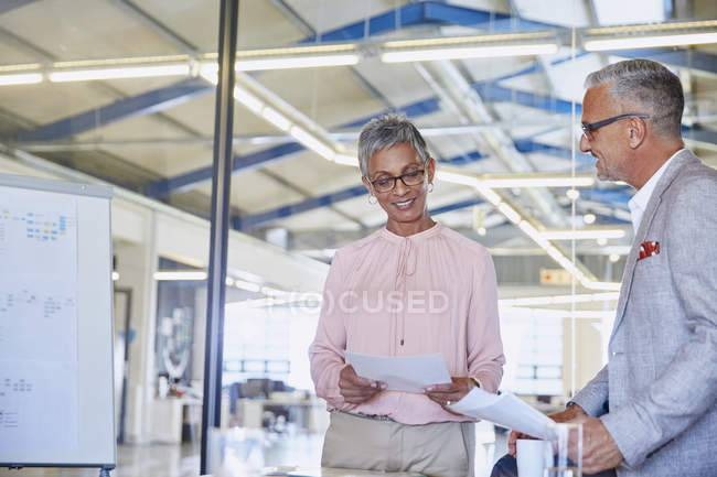 Businessman and businesswoman discussing paperwork at modern office — Stock Photo