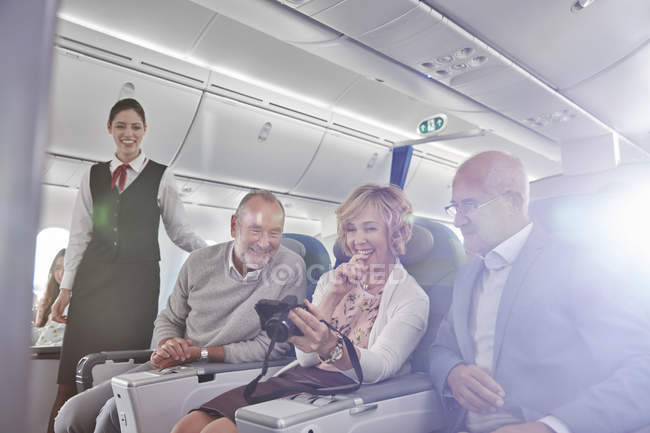 Friends looking at photos on digital camera on airplane — Stock Photo
