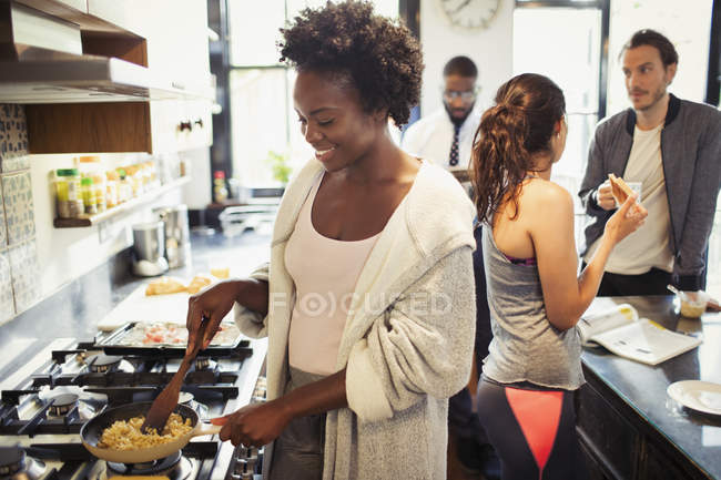 Woman cooking scrambled eggs at stove in kitchen — Stock Photo