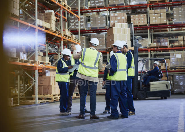 Gerente e trabalhadores reunidos em armazém de distribuição — Fotografia de Stock