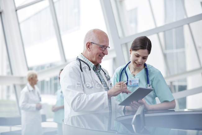Врач и медсестра с цифровым планшетом разговаривают в больнице — стоковое фото
