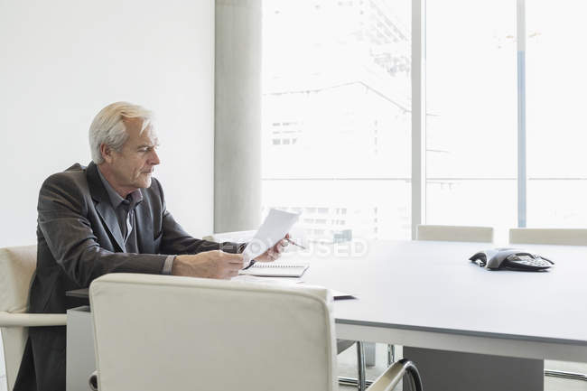 Старший бізнесмен розглядає документи в конференц-залі — стокове фото