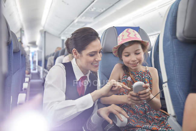Стюардеса допомагають дівчина пасажира з дистанційним управлінням на літак — стокове фото