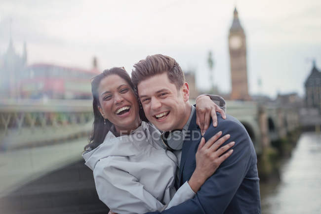 Retrato entusiasta, pareja de turistas riendo de pie en Westminster Bridge, Londres, Reino Unido - foto de stock