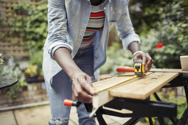 Frau mit Maßband misst Holz auf Terrasse — Stockfoto