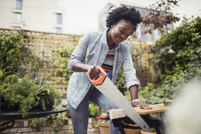 Woman with saw cutting wood — Stock Photo