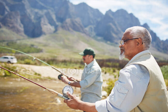 Homens seniores ativos amigos de pesca ao lado do lago ensolarado verão — Fotografia de Stock